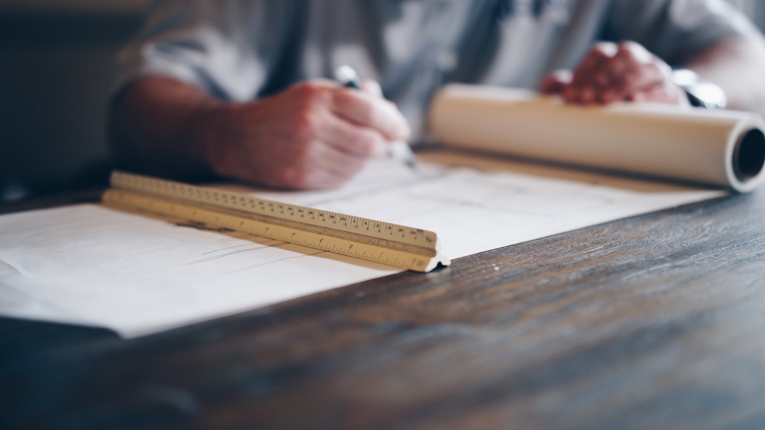 Designer sketching on plans with a scale ruler